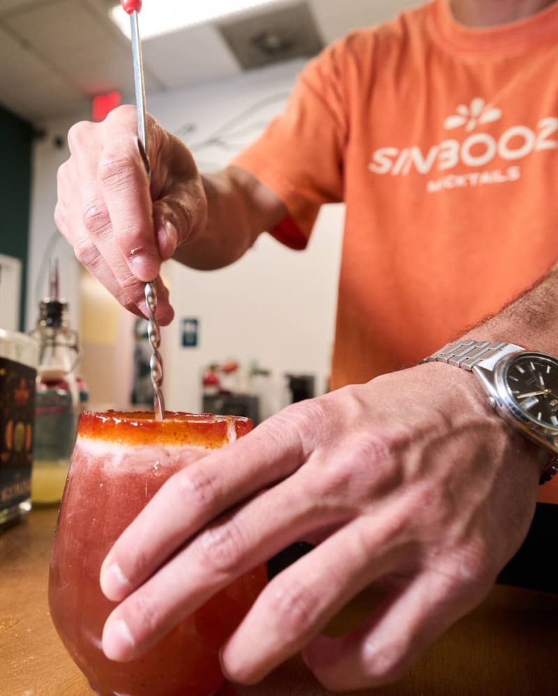 Aldo stirs a rimmed mocktail behind the Sin Booze bar