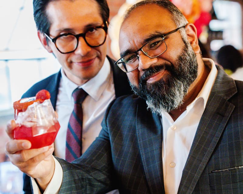 Two guests in suits raise their mocktails at a celebration