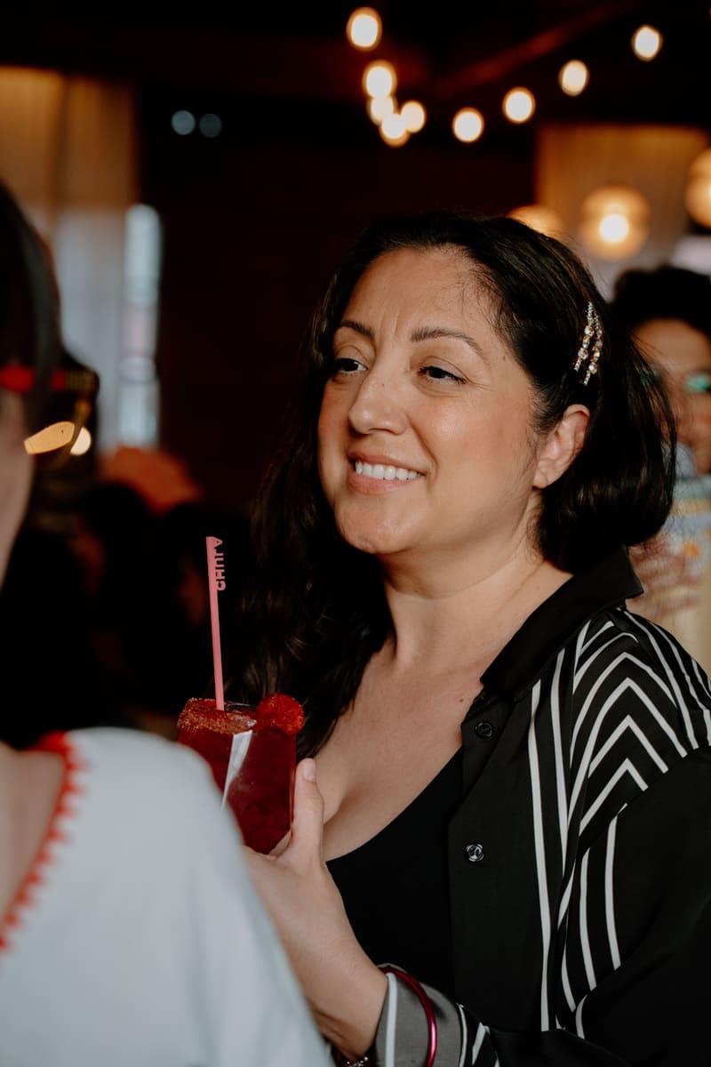 A smiling guest holds a red mocktail