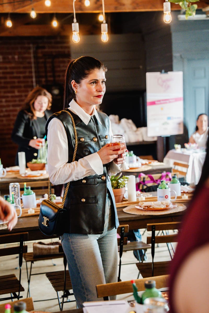 A guest holds a mocktail at a celebration in a brick event space
