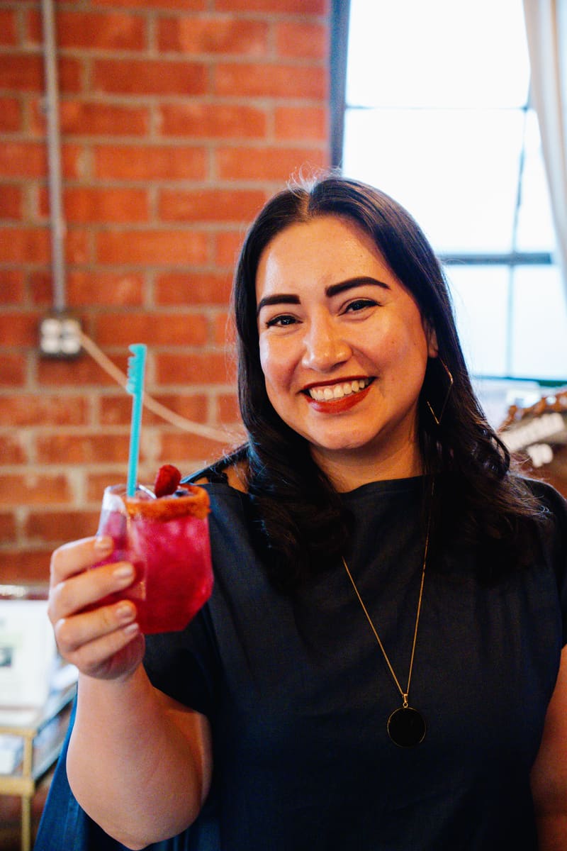 A smiling guest raises a pink zero-alcohol mocktail